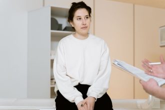Mulher adulta participa atentamente de uma consulta médica em uma clínica.