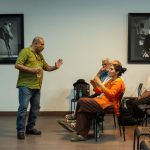Pessoa fala ao público em uma sala de conferências durante uma discussão coletiva.