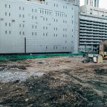 Canteiro de obras cercado por edifícios modernos em uma área urbana.