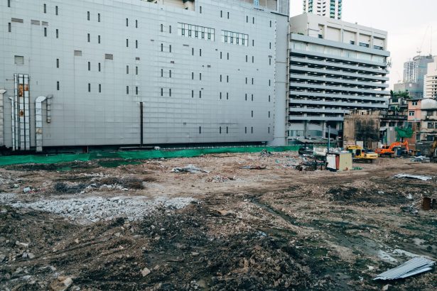 Canteiro de obras cercado por edifícios modernos em uma área urbana.